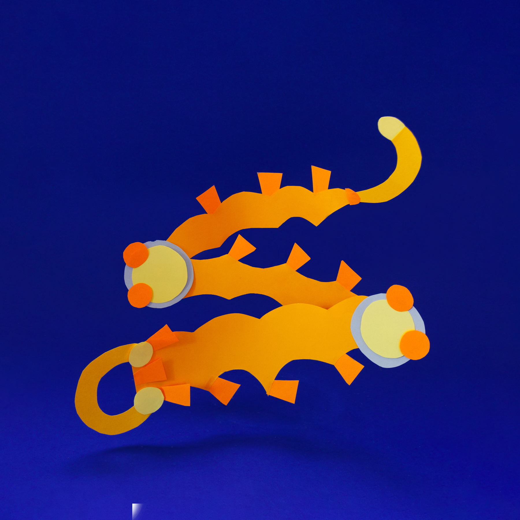 Two orange paper creatures before the misprint press